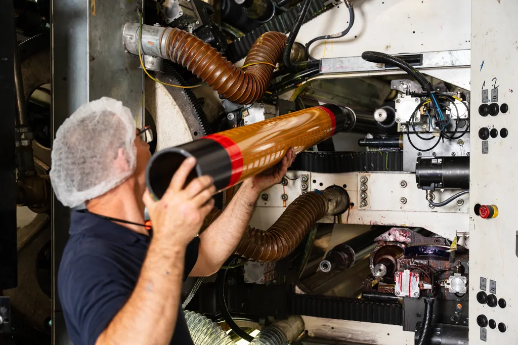Employee inserting a printed sleeve into the flexographic press